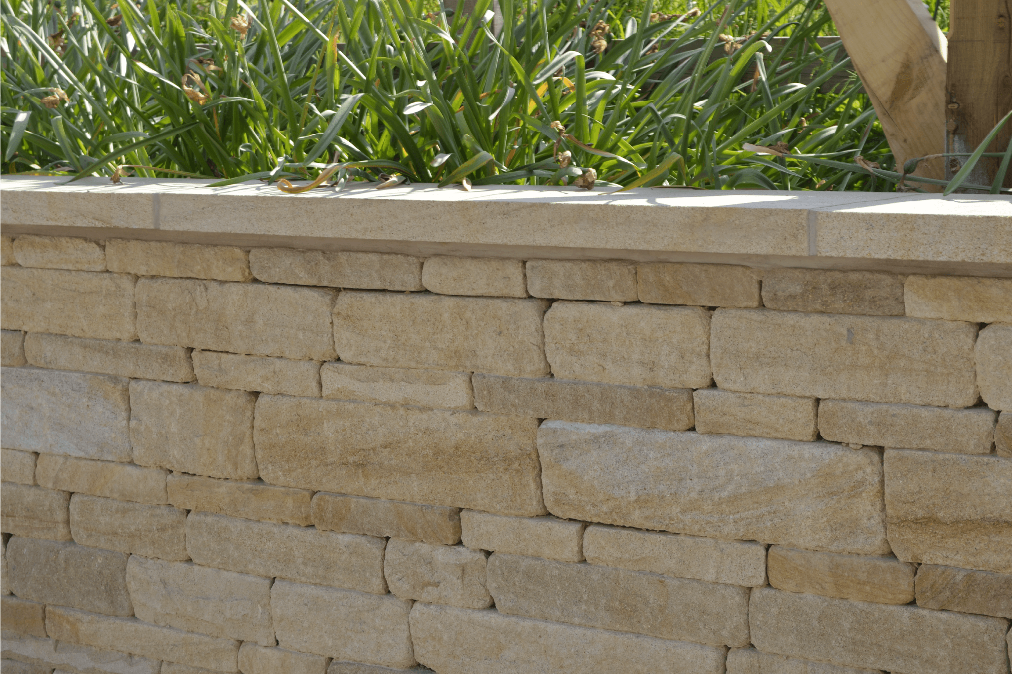 Close-up of natural stone walling with expertly placed coping stones, highlighting the precision in stone alignment and smooth coping finish.